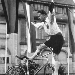 Das Foto zeigt einen Mann mit dunklen Haaren der auf einem Fahrrad balanciert vor den alten Frechener Rathaus.
